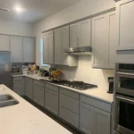 Modern kitchen with gray cabinetry, stainless steel appliances, and a spacious countertop, showcasing The Perfect Cabinet's remodeling services.
