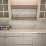 Modern kitchen cabinetry with white finish, marble countertop, and open shelving, showcasing custom cabinetry design by The Perfect Cabinet Company.