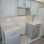 Kitchen featuring light blue cabinetry, white countertops, and a tiled backsplash, showcasing remodeling services by The Perfect Cabinet Company.