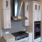 Modern kitchen design featuring white cabinetry, stainless steel appliances, and a decorative backsplash, showcasing The Perfect Cabinet Company's custom cabinetry and remodeling expertise.