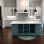Modern kitchen featuring a central blue island with open shelving, white cabinetry, and pendant lighting, showcasing The Perfect Cabinet Company's custom cabinetry and remodeling expertise.