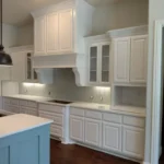Modern kitchen featuring white cabinetry, a central island, and under-cabinet lighting, showcasing custom cabinetry options for remodeling services.
