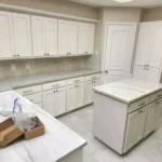 Modern kitchen with white cabinetry and marble countertops, showcasing a spacious layout ideal for remodeling and custom cabinetry projects by The Perfect Cabinet Company.
