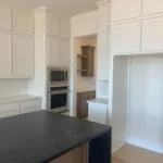 Modern kitchen featuring custom cabinetry, a central island with a dark countertop, and built-in appliances, showcasing The Perfect Cabinet Company's remodeling expertise.