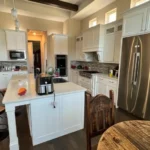 Modern kitchen featuring white cabinetry, stainless steel appliances, and an island with seating, showcasing The Perfect Cabinet Company's custom cabinetry and remodeling expertise.