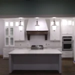 Modern kitchen design featuring white cabinetry, a central island with a marble countertop, and stainless steel appliances, showcasing The Perfect Cabinet Company's remodeling services.