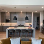 Modern kitchen with gray cabinetry, large island, bar stools, and pendant lighting, showcasing a stylish and functional design for remodeling projects.