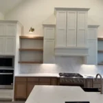 Modern kitchen design featuring custom cabinetry, white upper cabinets, and wooden lower cabinets, with a sleek countertop and built-in appliances.