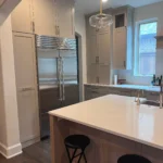 Modern kitchen with custom cabinetry, large refrigerator, and island with seating, showcasing The Perfect Cabinet's remodeling services.