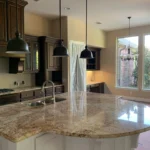 Modern kitchen featuring a large granite island, pendant lighting, and cabinetry, showcasing The Perfect Cabinet's remodeling expertise.