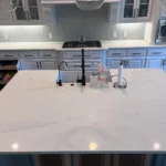 Modern kitchen island with white marble countertop, stylish black faucet, and kitchen accessories, showcasing custom cabinetry and remodeling services by The Perfect Cabinet Company.