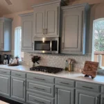 Modern kitchen design featuring custom cabinetry, a stainless steel microwave, and a gas stove, with natural light from windows and decorative elements on the countertop.