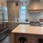 Modern kitchen interior featuring custom cabinetry, sleek stainless steel appliances, and a central island with seating, highlighting The Perfect Cabinet's remodeling expertise.