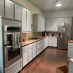 Modern kitchen with custom cabinetry, stainless steel appliances, and hardwood flooring, showcasing The Perfect Cabinet Company's remodeling services.