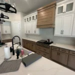 Modern kitchen with custom cabinetry, featuring a mix of white and wood finishes, stainless steel appliances, and a stylish countertop, showcasing The Perfect Cabinet's remodeling expertise.