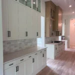 Modern kitchen with white cabinetry, sleek countertops, and wood flooring, showcasing custom cabinetry and remodeling services by The Perfect Cabinet Company.