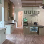 Modern kitchen interior featuring custom cabinetry, a large island with a dark countertop, and stainless steel appliances, showcasing a blend of functionality and style for remodeling projects by The Perfect Cabinet Company.