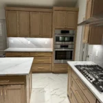Modern kitchen with custom cabinetry, marble countertops, and stainless steel appliances, showcasing a sleek design ideal for remodeling services.