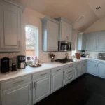 Modern kitchen with light gray cabinetry, marble countertops, and stainless steel appliances, showcasing a stylish and functional design for remodeling services.
