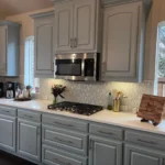 Modern kitchen with gray cabinetry, stainless steel microwave, gas stove, and decorative backsplash, showcasing The Perfect Cabinet Company's custom cabinetry and remodeling services.