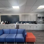 Modern kitchen interior featuring gray cabinetry, stainless steel appliances, and a blue and orange sectional sofa, showcasing a blend of style and functionality for remodeling inspiration.