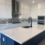Modern kitchen featuring a large white countertop, blue cabinetry, and a stylish black faucet, showcasing custom cabinetry and remodeling services by The Perfect Cabinet Company.