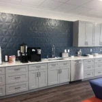 Modern kitchen design featuring gray cabinetry, a blue textured wall, and various kitchen appliances, showcasing The Perfect Cabinet Company's remodeling services.
