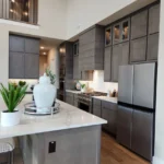 Modern kitchen featuring sleek gray cabinetry, stainless steel appliances, and a stylish island with a decorative vase and greenery, showcasing The Perfect Cabinet's custom cabinetry and remodeling expertise.
