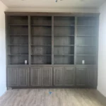 Custom cabinetry wall unit with open shelves and closed storage, showcasing craftsmanship for office remodeling.