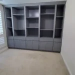 Modern gray cabinetry with open shelves and closed storage, showcasing custom design for office spaces, featured in The Perfect Cabinet gallery.