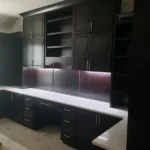 Modern black cabinetry with white countertop and under-cabinet lighting in an office setting, showcasing The Perfect Cabinet's design and craftsmanship.