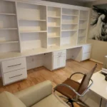 Modern office setup featuring white cabinetry, built-in shelves, and a stylish desk chair, showcasing The Perfect Cabinet's custom cabinetry solutions.
