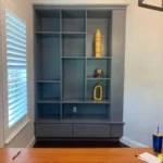 Modern gray cabinetry with open shelves and decorative items, showcasing The Perfect Cabinet's office design and cabinetry solutions.