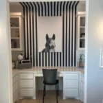 Modern office setup featuring white cabinetry, a sleek desk, and a decorative striped wall with a dog portrait, showcasing design ideas for home remodeling.