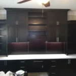 Modern dark cabinetry with open shelving and a white countertop in an office setting, showcasing The Perfect Cabinet's design and craftsmanship.
