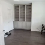 Modern office cabinetry with open shelving and a closed cabinet base, featuring a minimalist design in a bright room with hardwood flooring.