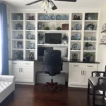 Home office setup featuring cabinetry with decorative plates, a desk with a computer, and a comfortable chair, showcasing The Perfect Cabinet's design and remodeling expertise.