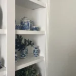 Cabinet shelving displaying blue and white decorative jars and greenery, showcasing elegant cabinetry design for The Perfect Cabinet's office gallery.