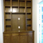 Wooden cabinetry installation featuring open shelves and a lower storage unit, designed for office organization and aesthetic appeal.