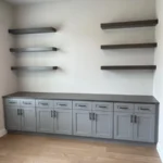 Modern gray cabinetry with multiple drawers and open shelving in a minimalist office setting.