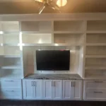 Modern white cabinetry with built-in shelving and a TV unit, showcasing the craftsmanship of The Perfect Cabinet in an office setting.