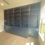 Modern blue cabinetry with open shelves and storage drawers in a well-lit office space, showcasing The Perfect Cabinet's craftsmanship and design.