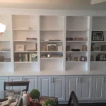 Custom cabinetry with open shelves and decorative items, showcasing a modern office space design by The Perfect Cabinet.