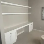 Office space featuring white cabinetry, a sleek desk area, and open shelving, showcasing The Perfect Cabinet's design capabilities for remodeling projects.