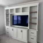 Modern white cabinetry with built-in TV unit and open shelving, showcasing sleek design for office or living space remodeling.
