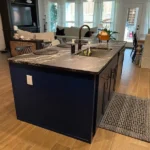 Custom kitchen island with dark cabinetry and a stone countertop, showcasing modern design elements and functional features, part of The Perfect Cabinet's gallery.
