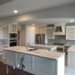 Custom kitchen island with white cabinetry, modern appliances, and spacious layout, showcasing The Perfect Cabinet's design expertise.