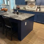 Custom kitchen island with blue cabinetry and marble countertop, featuring seating and modern kitchen decor, showcased in The Perfect Cabinet gallery.