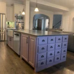 Custom kitchen island with purple cabinetry, multiple drawers, and stainless steel countertop, showcasing stylish design and storage options for modern kitchens.