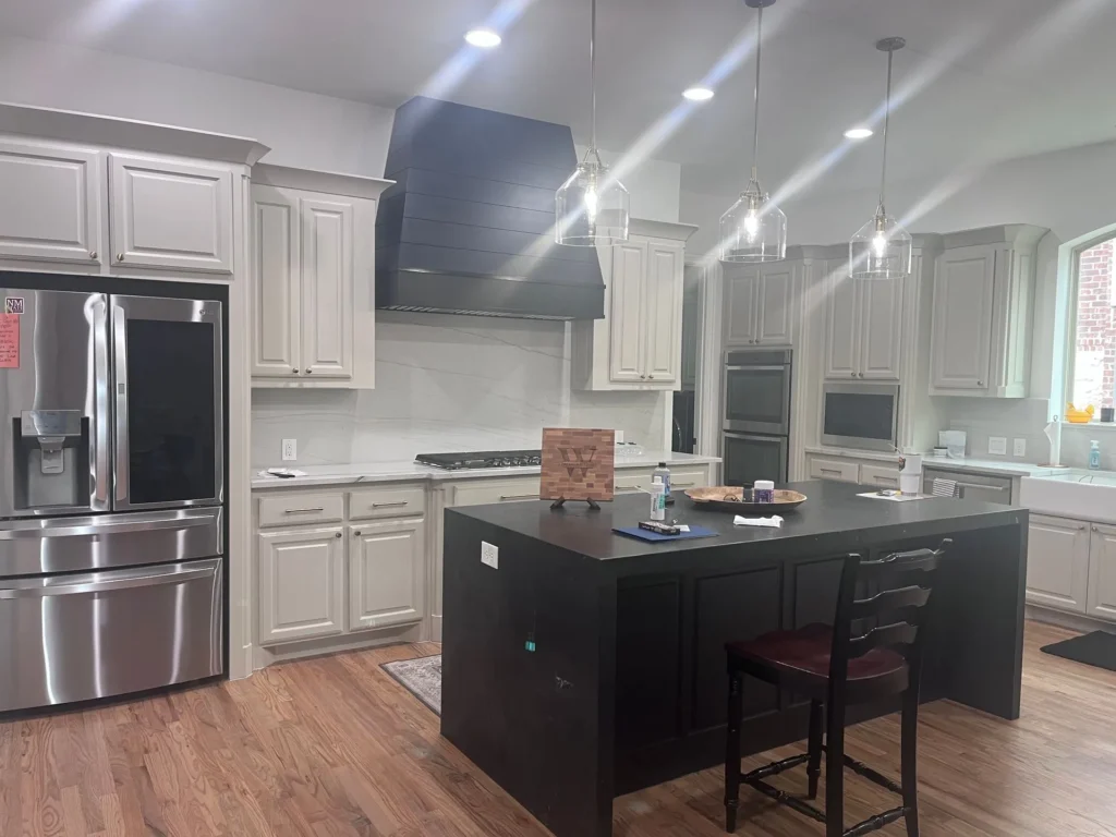 Modern kitchen featuring custom cabinetry, a large island with dark countertop, stainless steel appliances, and pendant lighting, reflecting The Perfect Cabinet Company's home remodeling services in Dallas.